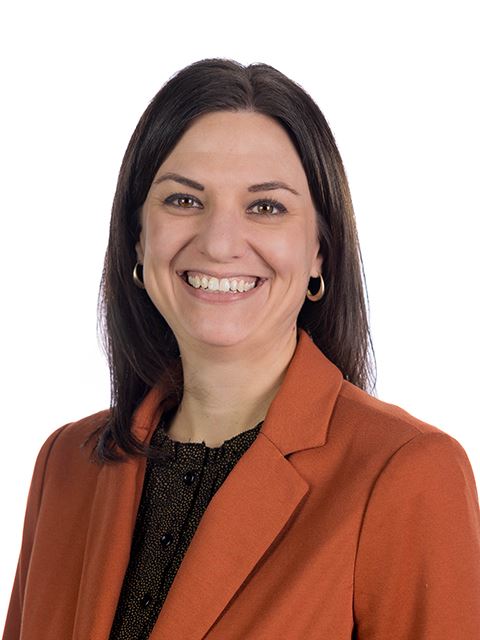 Portrait of Jacquie Kramer, library director, in a orange blazer over a blouse on white background