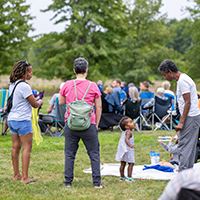 Adults standing around a toddler at the Bluegrass Festival in Washington County.