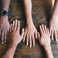 Different color hands placed on next to each other on a table. Opens in new window